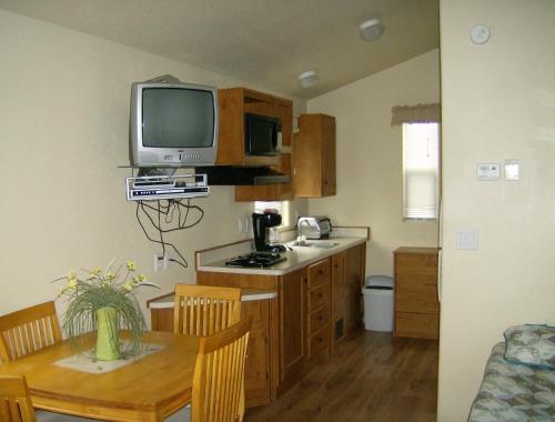 a kitchen with a table and a television on a wall at Lake Minden Camping Resort Cabin 1 in Nicolaus