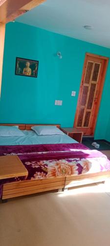 a bed in a room with a blue wall at Onarc guest house in Kasol