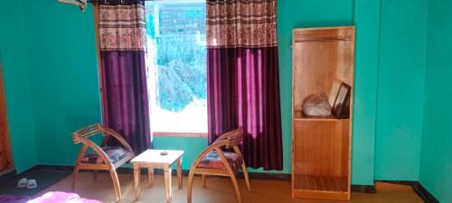 a room with two chairs and a table and a window at Onarc guest house in Kasol
