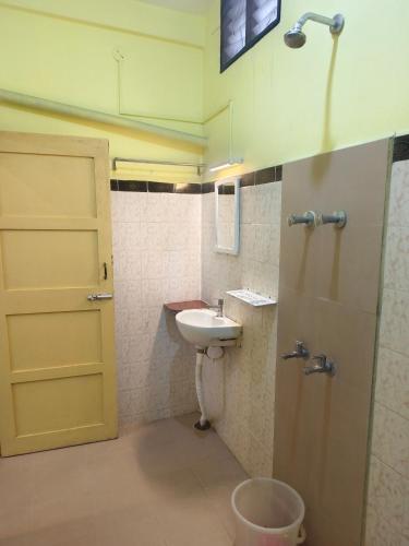 a bathroom with a sink and a toilet and a door at Silver Moon Guest House in Mahabalipuram