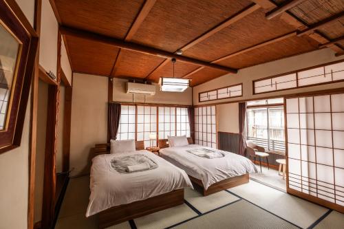 a bedroom with two beds in a room with windows at Snow Monkey Lodge in Yamanouchi