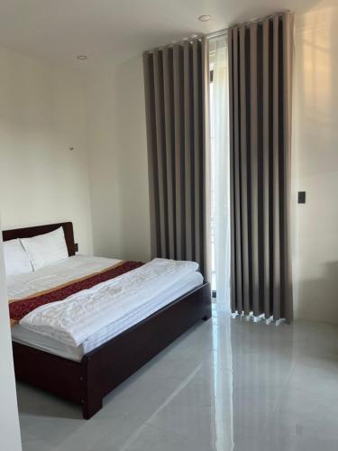 a bedroom with a bed and a window with curtains at Green Hotel in Khánh Dương