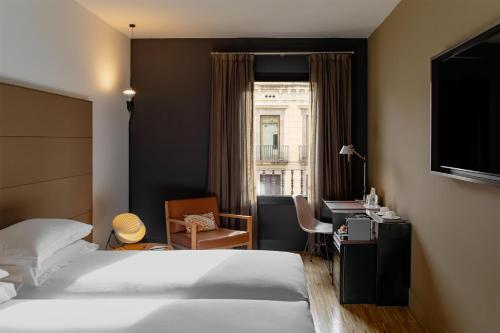 a hotel room with a bed and a desk and a window at Alexandra Barcelona Hotel, Curio Collection by Hilton in Barcelona