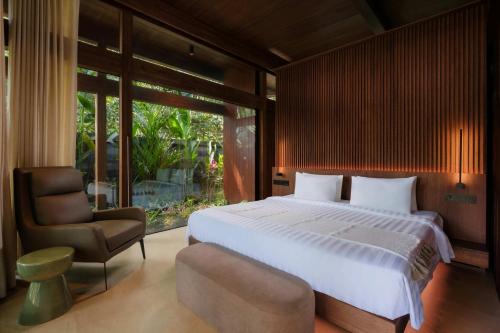 a bedroom with a large bed and a chair at Hot Stone Club Ubud in Ubud