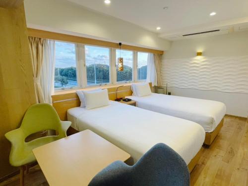 a room with two beds and a table and a chair at BREATH HOTEL in Fujisawa