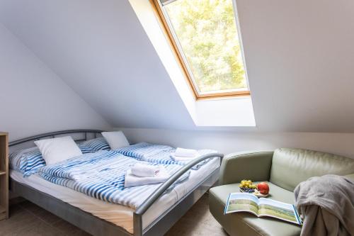a bed and a couch in a room with a window at Dollár Apartman in Orfű