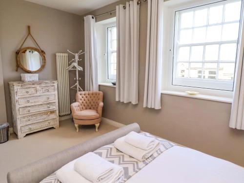 a bedroom with a bed and a chair and a mirror at Treetops, Alnwick in Alnwick