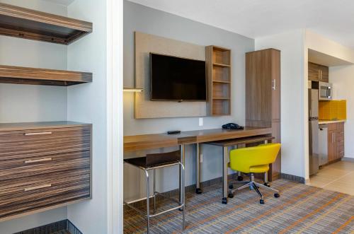 a hotel room with a desk and a yellow chair at MainStay Suites Great Falls Airport in Great Falls