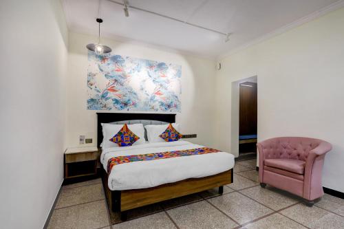 a bedroom with a bed and a pink chair at FabHotel Kences Inn in Chennai