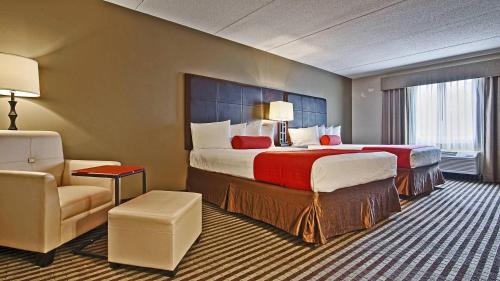 a hotel room with two beds and a chair at Comfort Inn & Suites Copley Akron in Copley