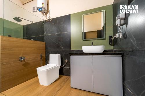 a bathroom with a sink and a toilet and a mirror at StayVista at Jungle Jade with WiFi in Madikeri