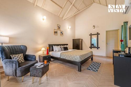 a bedroom with a bed and a couch and a chair at StayVista at Jungle Jade with WiFi in Madikeri