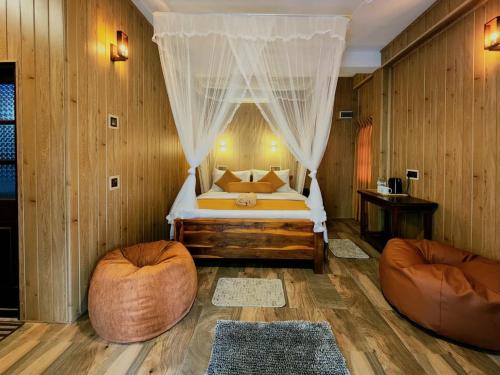 a bedroom with a bed with curtains and two chairs at Tea Brook Lodge Ella in Ella