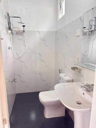 a white bathroom with a toilet and a sink at Hillcrest Bungalow in Matale
