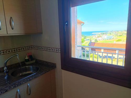 a kitchen with a sink and a window with a view at Apartamentos Eira Do Mar Sanxenxo in Aios