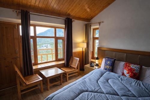 a bedroom with a bed and a desk and a window at Hotter Potter Stays Manali in Vashisht