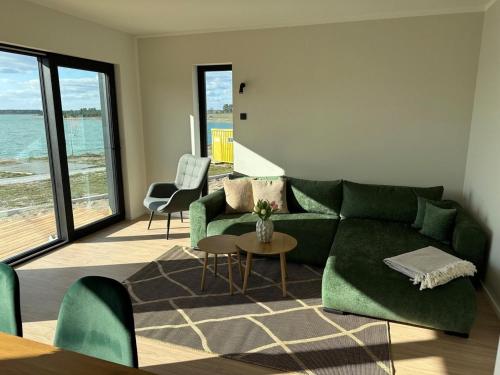 a living room with a green couch and a table at Ferienhaus Sonnenperle am Partwitzer See in Klein Partwitz