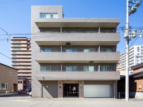 a tall building with a parking garage in front of it at Sapporo Residential Juno in Sapporo