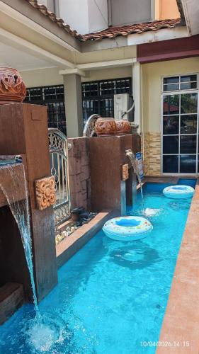 a swimming pool with a water fountain in a house at Homestay Santai Bertam in Kepala Batas