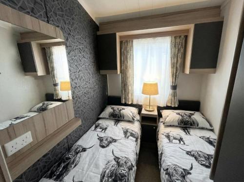 a small room with two beds and a window at Wild Thistle static Caravan in Kirkcolm