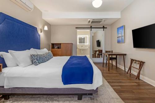 a bedroom with a large bed with a blue headboard at The Colonial Inn, an Ascend Collection Hotel in Hillsborough