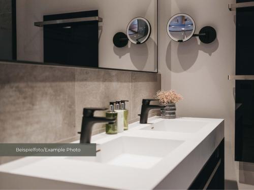 a bathroom with two sinks and two mirrors at VAYA Post Montafon - Neueröffnung Dezember 2026 in Gaschurn