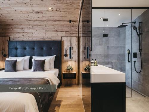 a bedroom with a bed and a shower and a sink at VAYA Post Montafon - Neueröffnung Dezember 2026 in Gaschurn