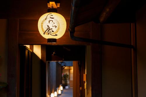 a light hanging from the ceiling of a building with lights at Tawara-an in Kyoto