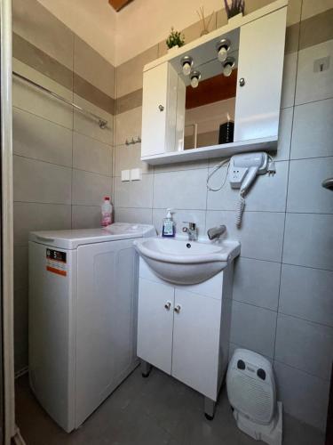 a white bathroom with a sink and a mirror at Tsitsinos maisonette house in Zekros