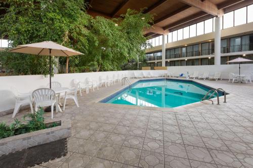 a pool with chairs and an umbrella next to a building at Wyndham Garden Detroit Metro Airport in Romulus