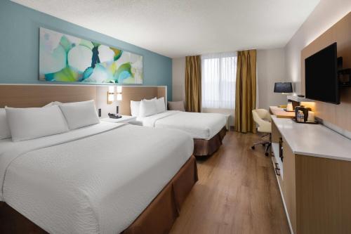 a hotel room with two beds and a flat screen tv at Wyndham Garden Detroit Metro Airport in Romulus