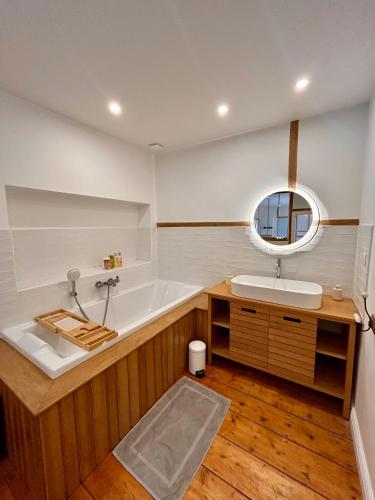 a bathroom with a tub and a sink and a mirror at Maison de campagne en plein centre de Senlis in Senlis