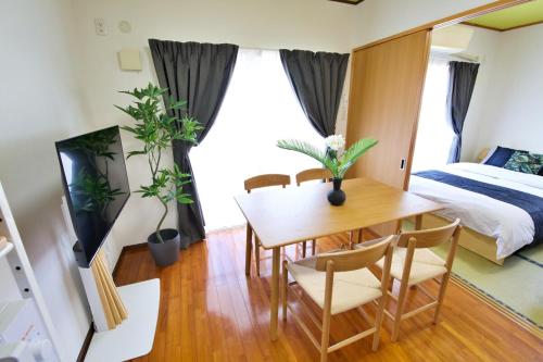 a room with a table and chairs and a bed at カラハーイもとぶ 碧 in Motobu