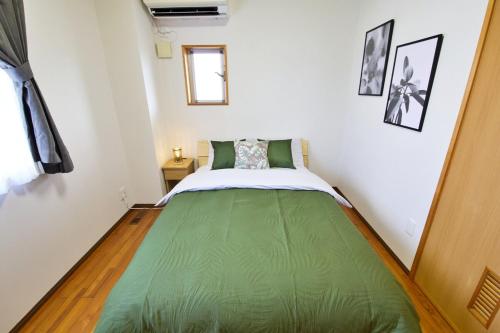 a small bedroom with a green bed in a room at カラハーイもとぶ 碧 in Motobu