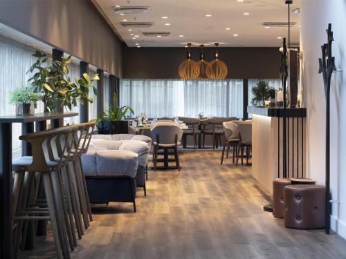 a restaurant with a bar and tables and chairs at Radisson Blu Hotel, Trondheim Airport in Stjoerdal