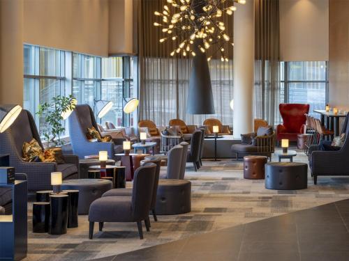 a lobby with chairs and tables and a chandelier at Radisson Blu Hotel, Trondheim Airport in Stjoerdal