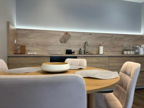 a kitchen with a wooden table with white chairs at Premier Hotel Miskolc in Miskolc