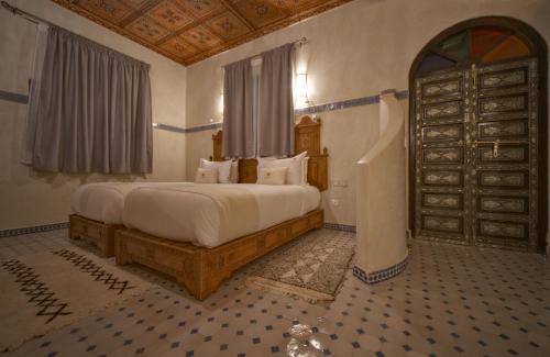 a bedroom with a large bed and a door at OZ Palace Ouarzazate & SPA in Ouarzazate