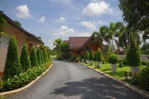 a driveway with a row of trees and a house at Lay de Bua Resort in Phatthalung