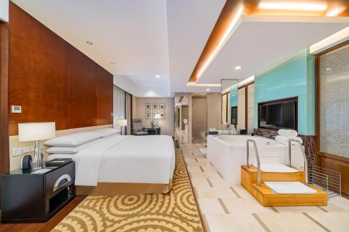 a bedroom with a bed and a tub and a television at The Imperial Mansion, Beijing - Marriott Executive Apartments in Beijing