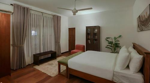 a bedroom with a white bed and a chair at Villa Barracuda in Sri Jayewardenepura Kotte