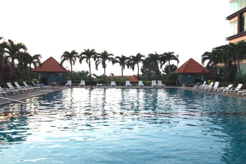 a large swimming pool with chairs and palm trees at View Talay 6 by Pat 42 in Pattaya Central