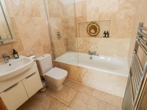 a bathroom with a tub and a toilet and a sink at Rose Apartment - Gower in Swansea