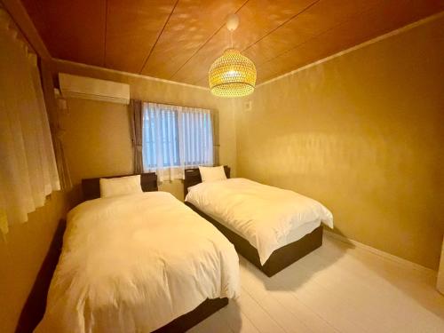a bedroom with two beds and a chandelier at Villa Monica 30sec in Noritake-Shinmachi