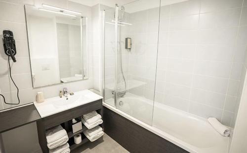 a white bathroom with a sink and a shower at Hôtel du Parc & Spa in Hossegor