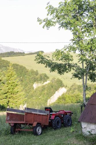 a red tractor pulling a trailer in a field at Čemerno Mountain House in Gacko