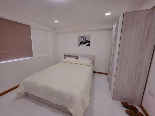 a white bedroom with a bed and a window at Hugg daily airport 1 in Samutprakarn