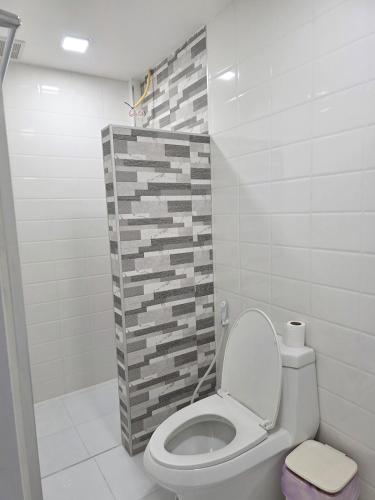 a bathroom with a toilet and a tile wall at Hugg daily airport 1 in Samutprakarn