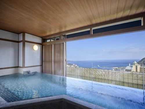 a swimming pool with a view of the ocean at KAMENOI HOTEL Atami Annex in Atami