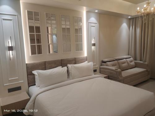 a bedroom with a large white bed and a chair at Shagun Hotel & Resorts in Khandwa